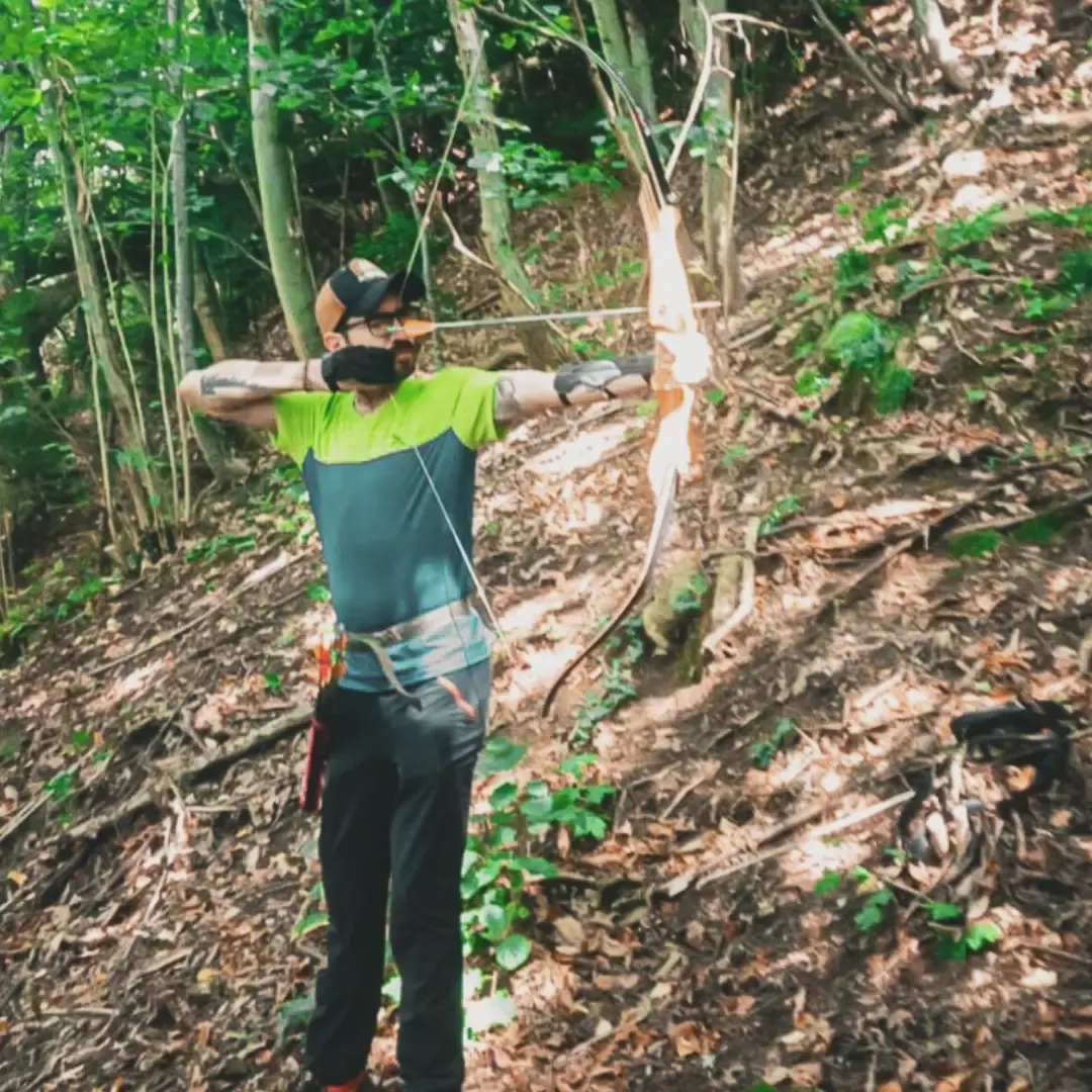 Tiro con l'arco tra gli alberi in pendenza