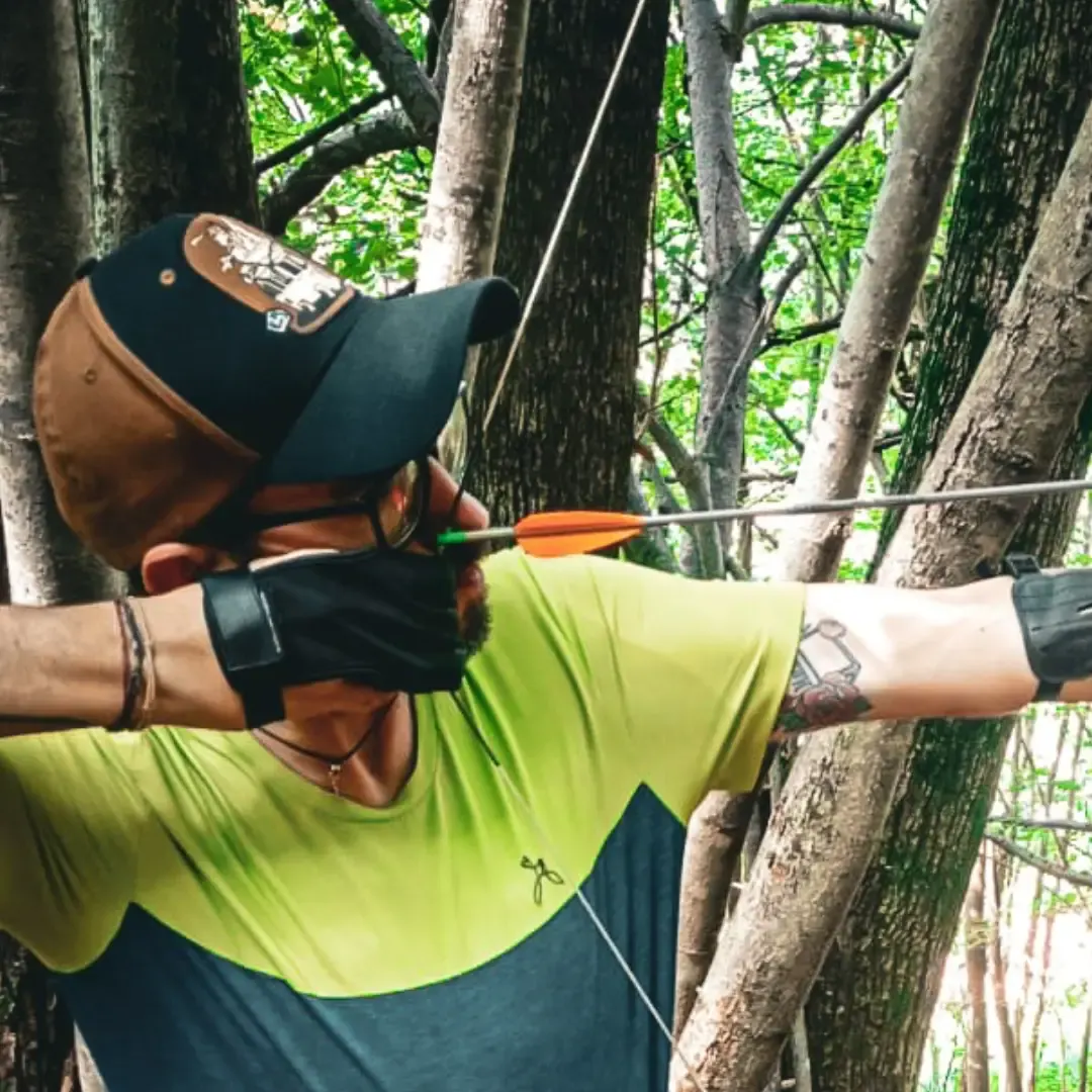 Allievo che mira con l'arco tra gli alberi