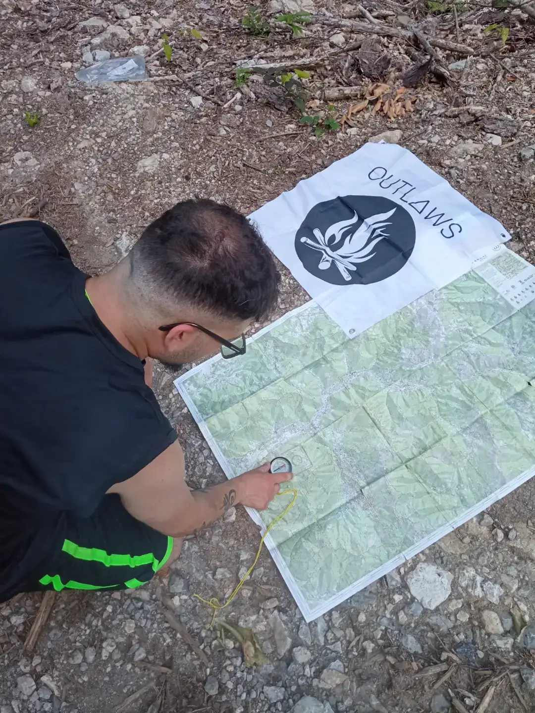 Lettura della carta con la bussola, telo OUTLAWS a terra
