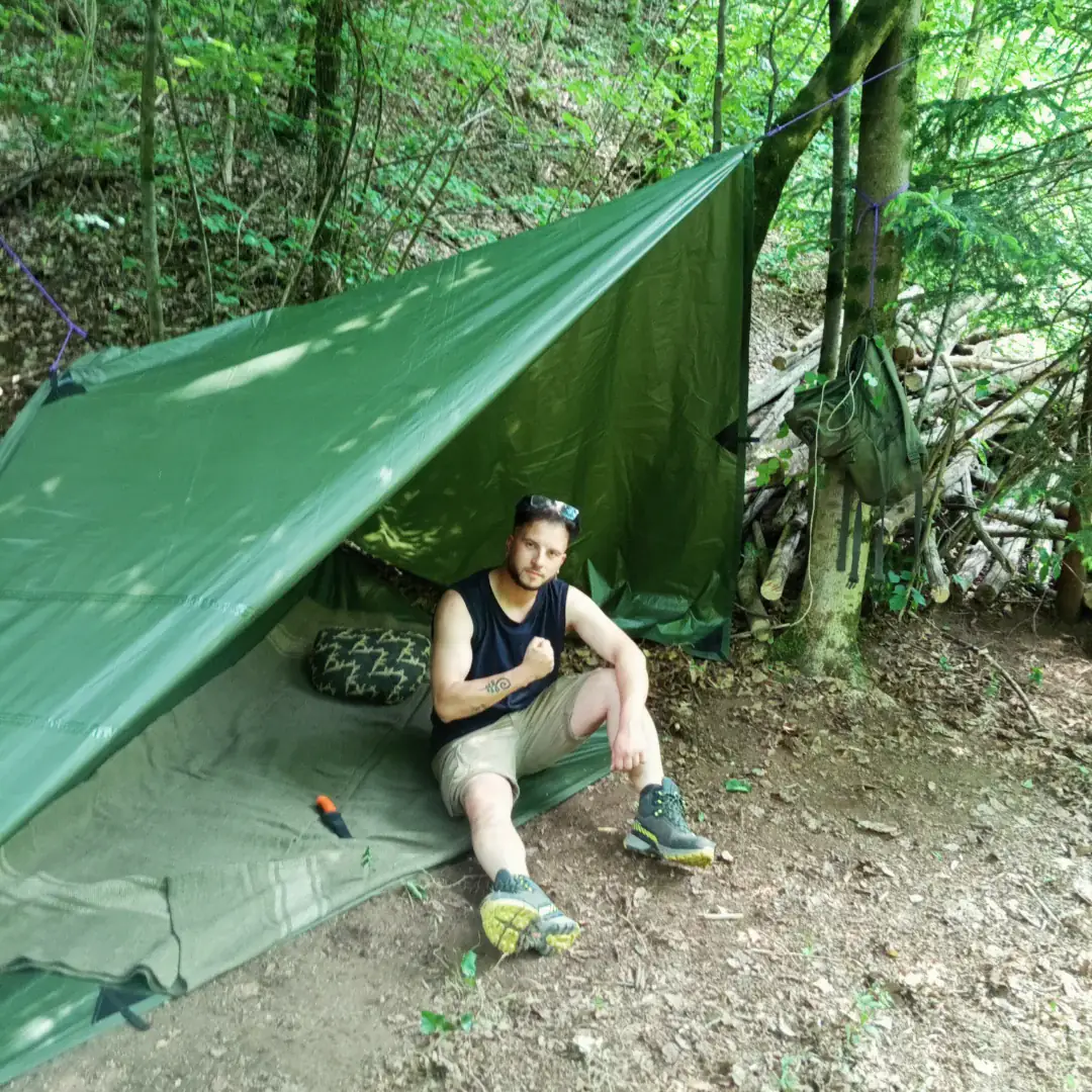Allievo seduto sotto un telo teso a riparo nel bosco
