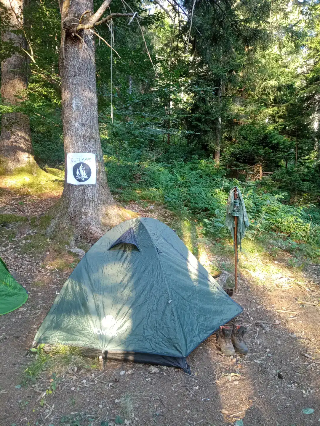 Tenda e bandiera OUTLAWS tra gli alberi